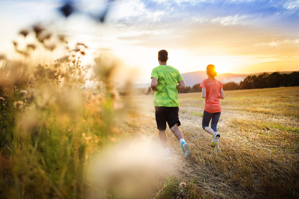 couple running outside in a field as part of a healthy lifestyle