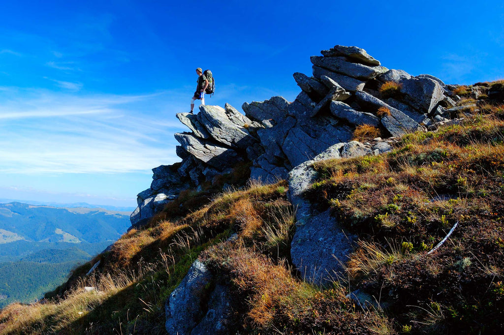 man-hiking-standing-on-rocks