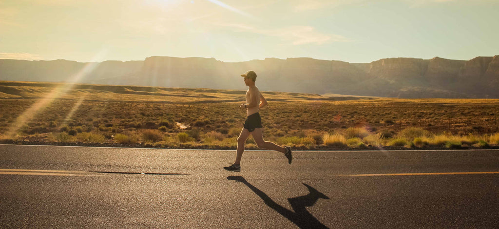 man running on a highway in the middle of the desert