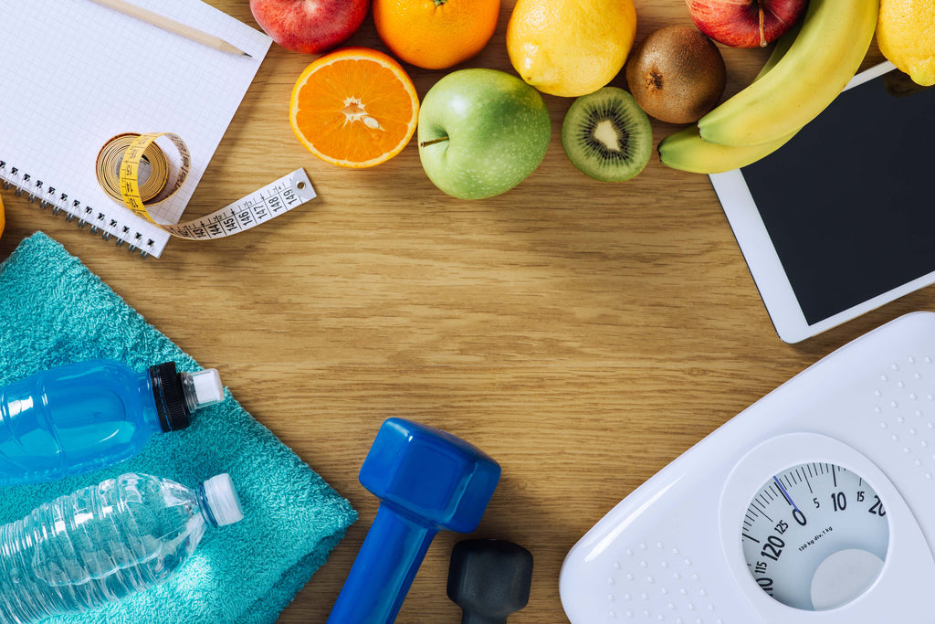 water bottles, dumbells, weight scale, fruit, a notepad and pencil